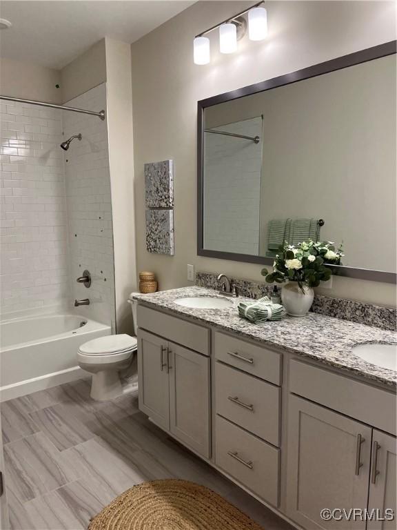 full bathroom with toilet, tiled shower / bath, and vanity