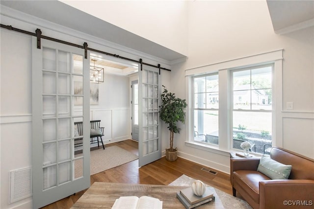 interior space with hardwood / wood-style floors, ornamental molding, a notable chandelier, and a barn door