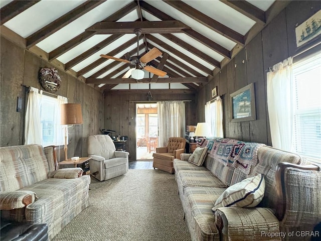 carpeted living room featuring beam ceiling, ceiling fan, wood walls, and high vaulted ceiling