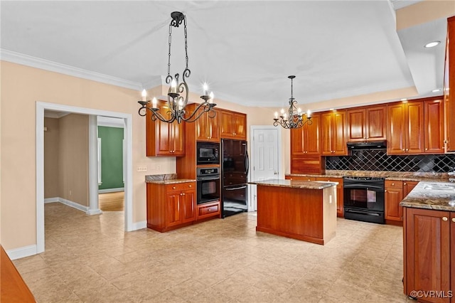 kitchen featuring black appliances, a kitchen island, decorative light fixtures, an inviting chandelier, and light stone counters