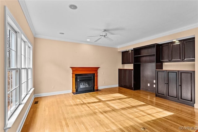 unfurnished living room with ceiling fan, crown molding, and light wood-type flooring