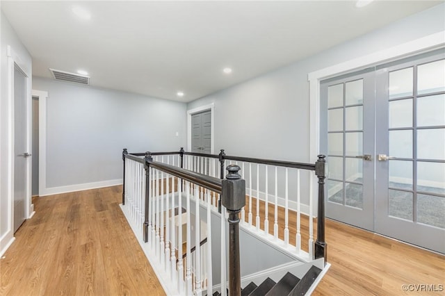 corridor featuring french doors, wood finished floors, recessed lighting, and an upstairs landing