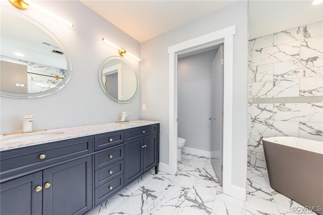 bathroom featuring a sink, marble finish floor, a soaking tub, double vanity, and toilet