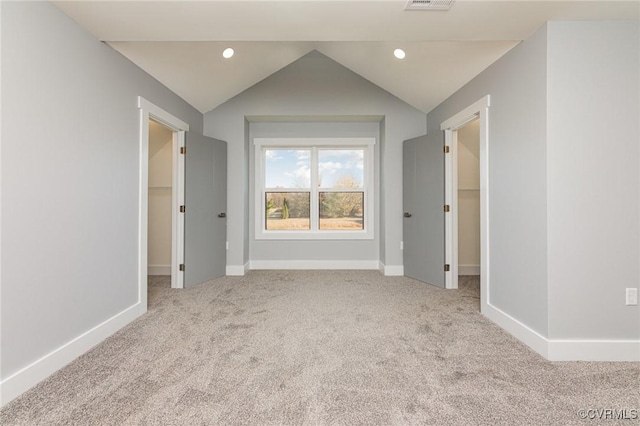 carpeted empty room featuring lofted ceiling, baseboards, recessed lighting, and visible vents