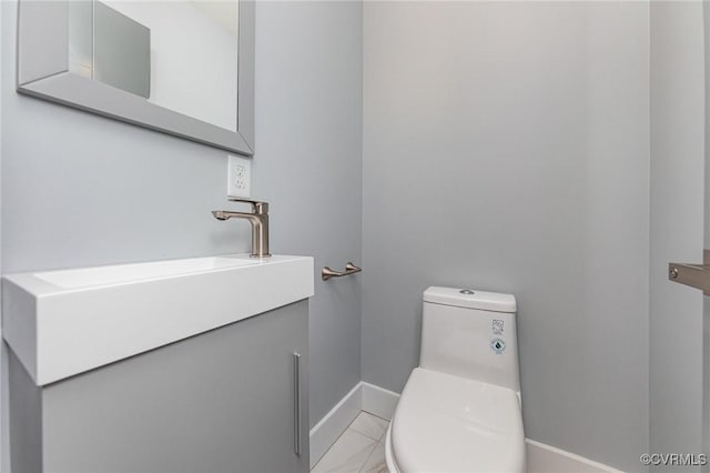 bathroom featuring marble finish floor, vanity, toilet, and baseboards