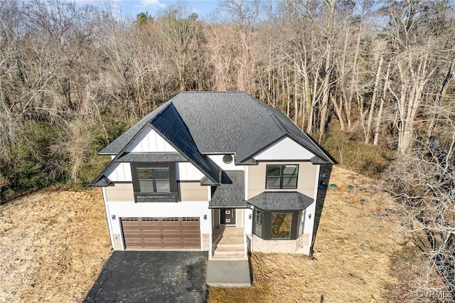 view of front of property featuring aphalt driveway, board and batten siding, a shingled roof, and a garage