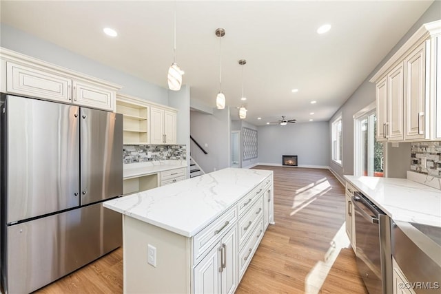 kitchen with open shelves, decorative backsplash, a kitchen island, and appliances with stainless steel finishes