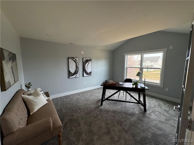 office area featuring dark carpet, vaulted ceiling, visible vents, and baseboards