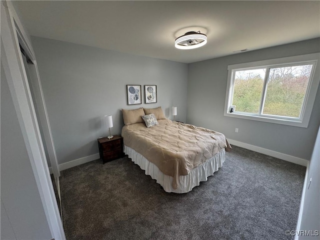 bedroom with dark colored carpet and baseboards