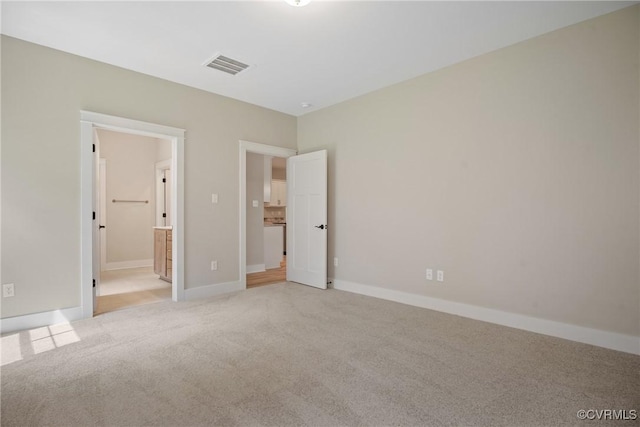 unfurnished bedroom with baseboards, connected bathroom, visible vents, and light colored carpet