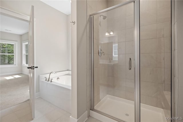 bathroom with tile patterned floors, a shower stall, baseboards, and a bath