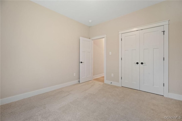 unfurnished bedroom featuring light carpet, baseboards, and a closet