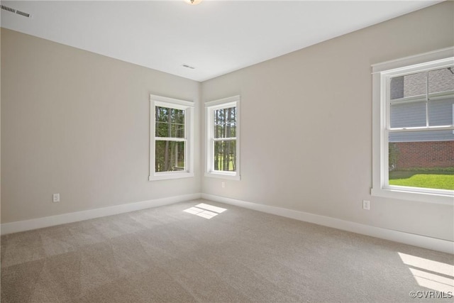 carpeted spare room with visible vents and baseboards