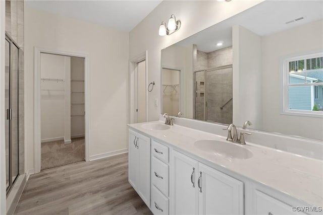 bathroom with a walk in closet, visible vents, a sink, and a shower stall