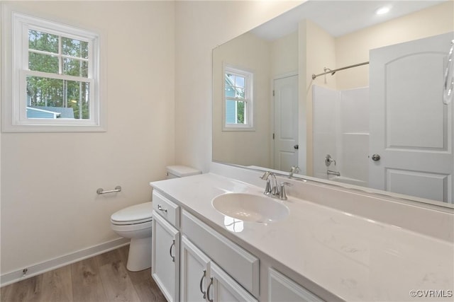 bathroom with plenty of natural light, vanity, baseboards, and wood finished floors