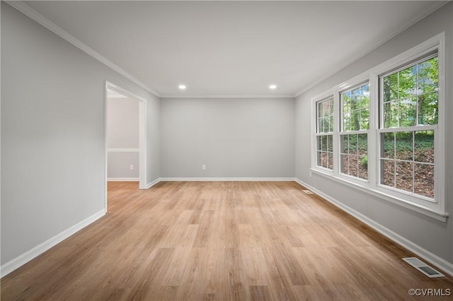 empty room featuring light wood-type flooring and ornamental molding