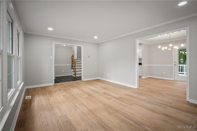 spare room with wood-type flooring, an inviting chandelier, and ornamental molding