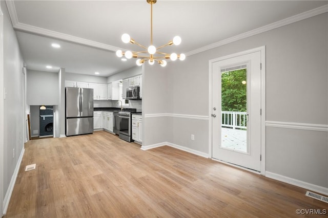 kitchen featuring white cabinets, appliances with stainless steel finishes, backsplash, hanging light fixtures, and a notable chandelier