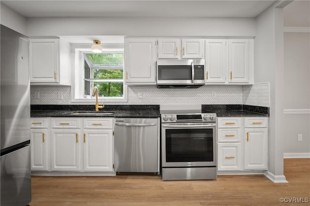 kitchen featuring white cabinets, appliances with stainless steel finishes, dark stone counters, tasteful backsplash, and sink