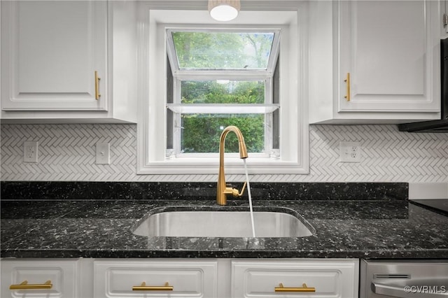 kitchen featuring dishwasher, sink, dark stone countertops, and white cabinetry