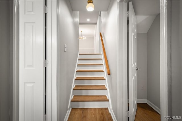 staircase featuring a chandelier and hardwood / wood-style flooring