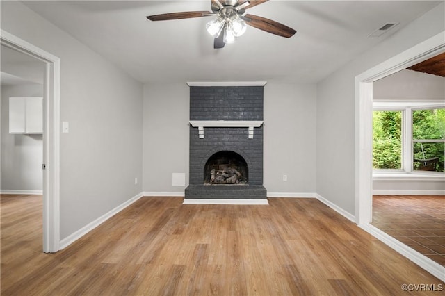 unfurnished living room featuring ceiling fan, a fireplace, and wood-type flooring