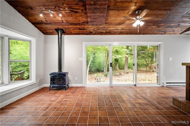 unfurnished living room with wood ceiling, plenty of natural light, a wood stove, and a baseboard radiator