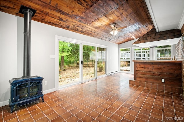 unfurnished sunroom featuring ceiling fan, a baseboard heating unit, lofted ceiling with beams, wood ceiling, and a wood stove