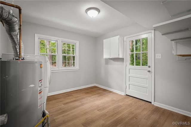 interior space with cabinets, a healthy amount of sunlight, water heater, and light wood-type flooring