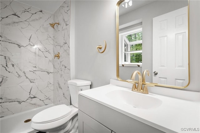 bathroom featuring toilet, vanity, and a tile shower