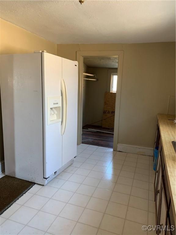 kitchen with white refrigerator with ice dispenser and a textured ceiling