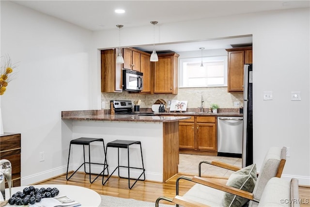 kitchen featuring sink, decorative light fixtures, a kitchen breakfast bar, kitchen peninsula, and stainless steel appliances