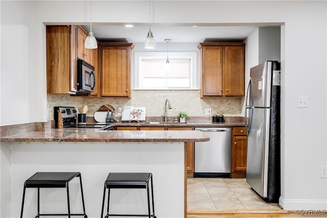 kitchen featuring sink, a breakfast bar, appliances with stainless steel finishes, hanging light fixtures, and kitchen peninsula