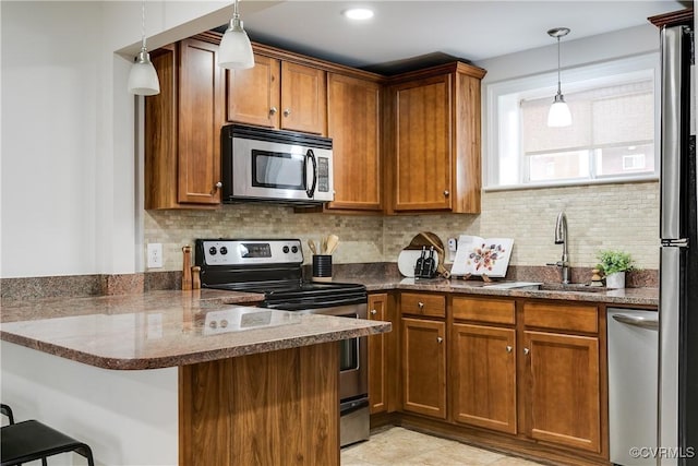 kitchen featuring a kitchen bar, sink, tasteful backsplash, appliances with stainless steel finishes, and kitchen peninsula