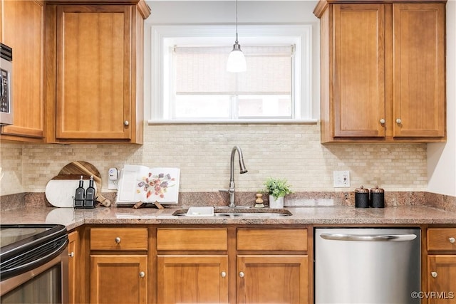 kitchen featuring decorative light fixtures, appliances with stainless steel finishes, sink, and decorative backsplash