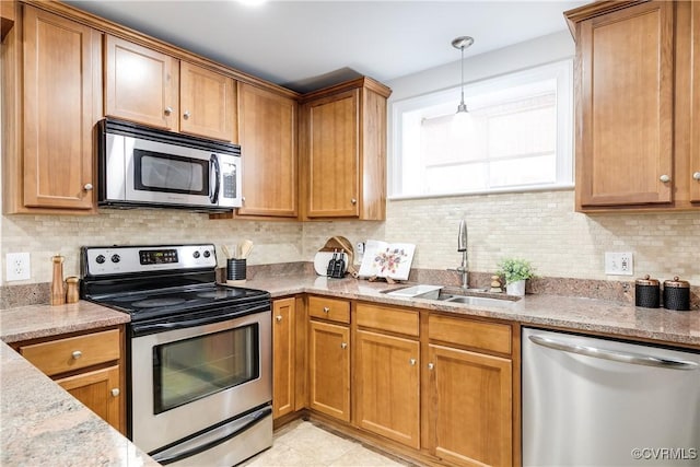 kitchen with appliances with stainless steel finishes, sink, decorative backsplash, light tile patterned floors, and light stone counters