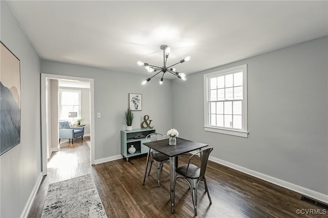 dining room with dark hardwood / wood-style flooring and an inviting chandelier