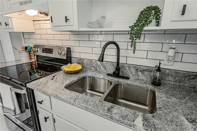 kitchen with white cabinetry, backsplash, electric range, light stone counters, and sink