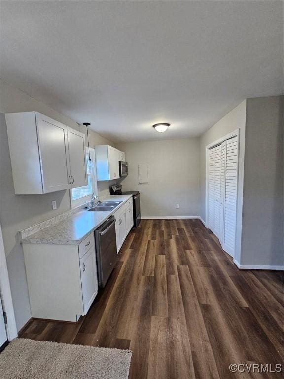 kitchen with pendant lighting, dark wood-type flooring, white cabinetry, stainless steel appliances, and sink