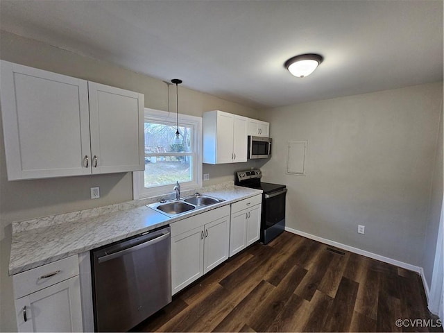 kitchen featuring white cabinets, appliances with stainless steel finishes, decorative light fixtures, dark wood-type flooring, and sink