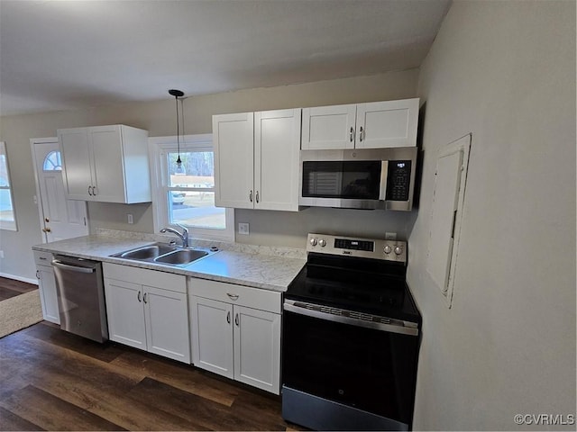 kitchen featuring white cabinets, decorative light fixtures, dark wood-type flooring, stainless steel appliances, and sink