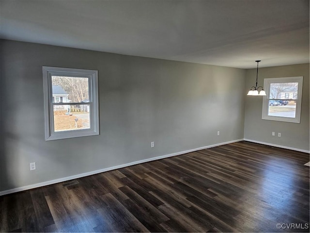 unfurnished room featuring an inviting chandelier and dark hardwood / wood-style floors