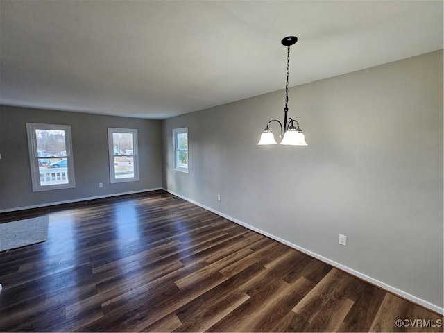 empty room featuring dark hardwood / wood-style floors and an inviting chandelier