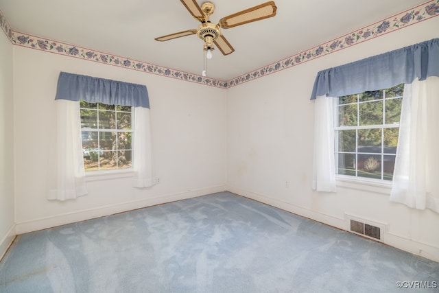 carpeted empty room featuring ceiling fan and a wealth of natural light