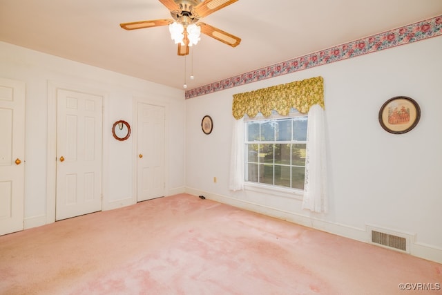 unfurnished bedroom with ceiling fan, two closets, and carpet flooring