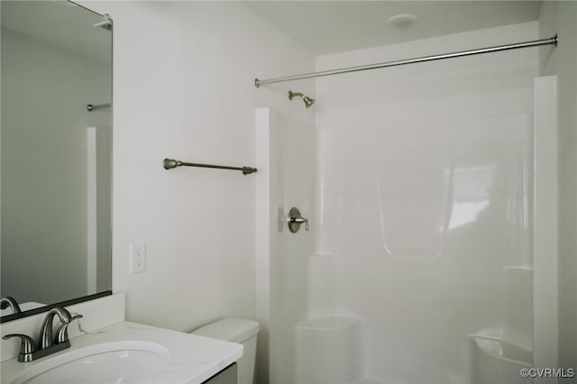 bathroom featuring toilet, vanity, and a shower