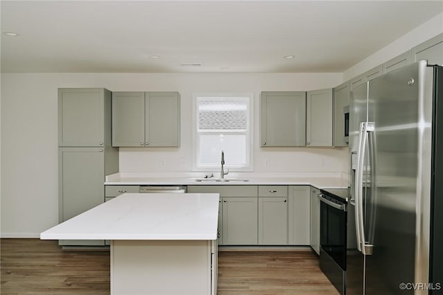 kitchen featuring a kitchen island, dark hardwood / wood-style flooring, stainless steel appliances, sink, and gray cabinets