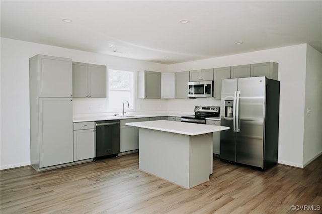 kitchen with gray cabinets, a kitchen island, sink, light hardwood / wood-style flooring, and stainless steel appliances