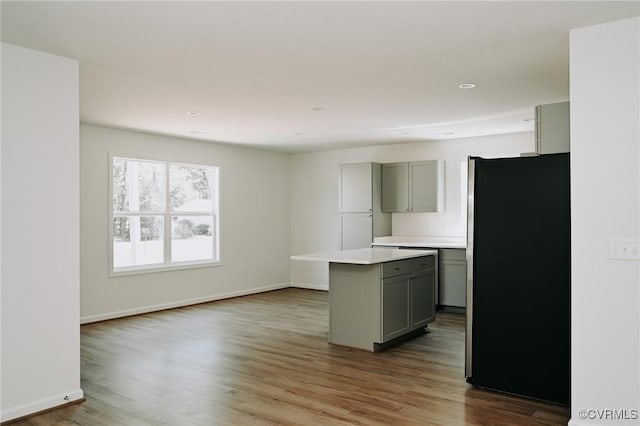 kitchen featuring hardwood / wood-style floors, a kitchen island, gray cabinetry, and stainless steel fridge