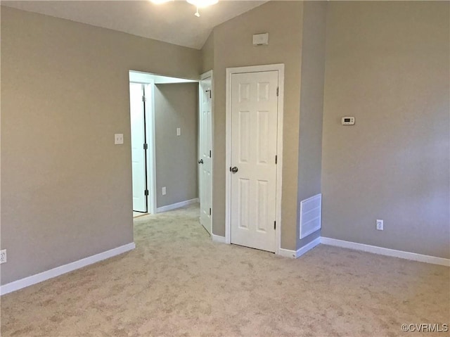 carpeted empty room featuring vaulted ceiling